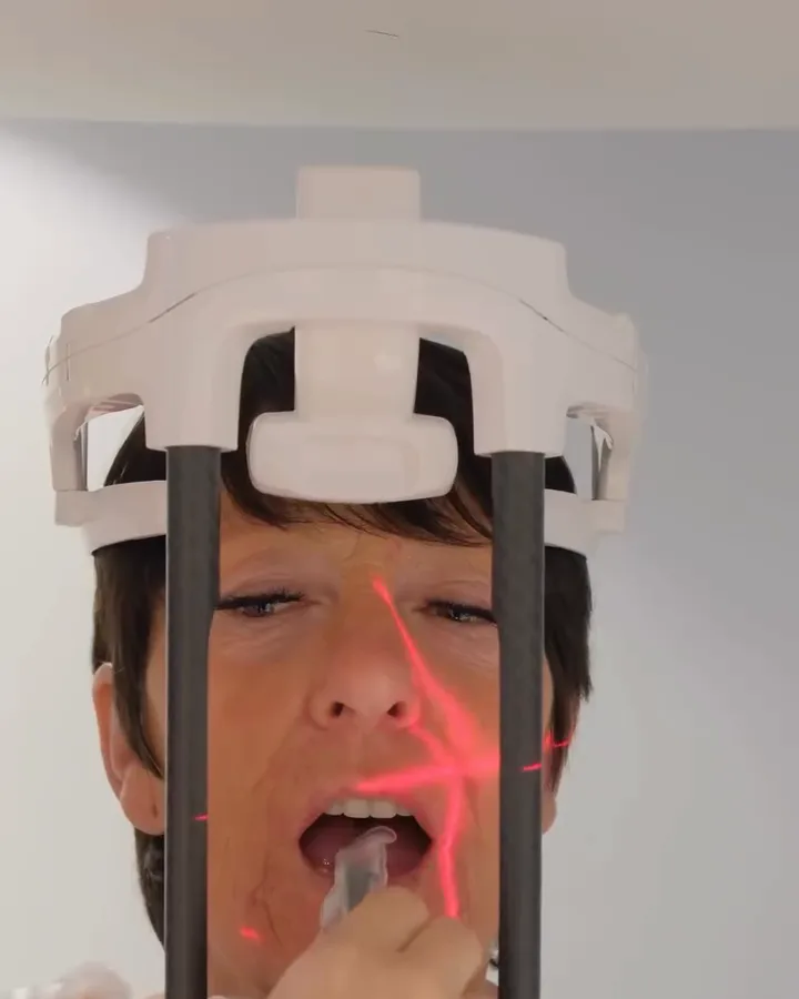 A patient in the panoramic X-ray unit at our clinic, with the alignment laser on