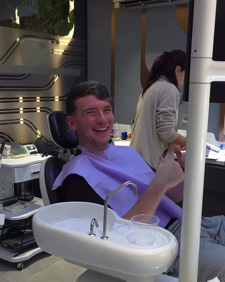 A patient smiling in the chair in a treatment room at our clinic, a team member working alongside